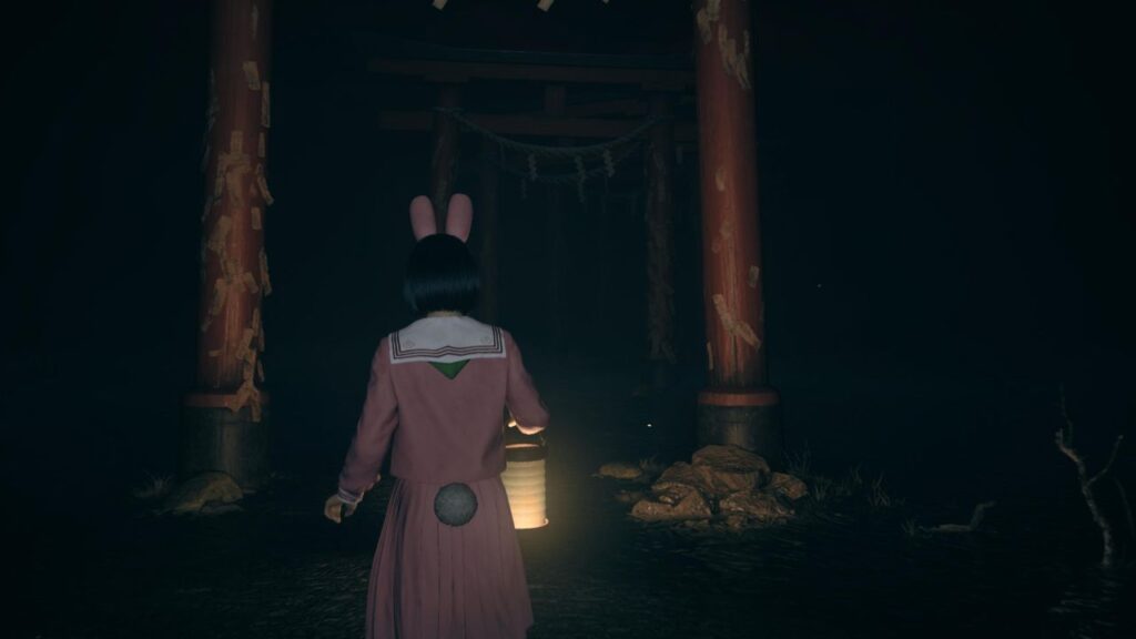 Postava s lampášom kráča pod červenými torii bránami – Silent Hill F